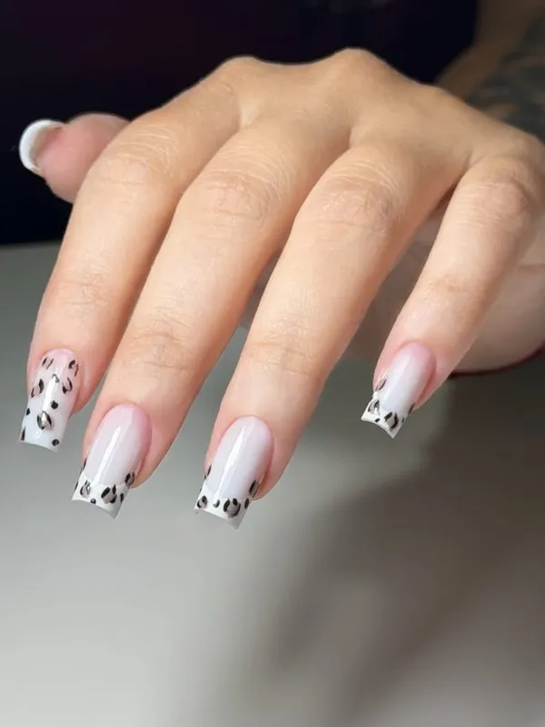 Mão com unhas alongadas em francesinha branca e detalhes de estampa de onça