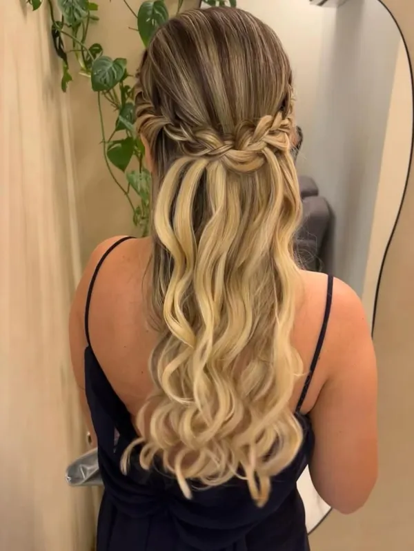 Mulher de costas com cabelo loiro em ondas longas e trança lateral em meio penteado