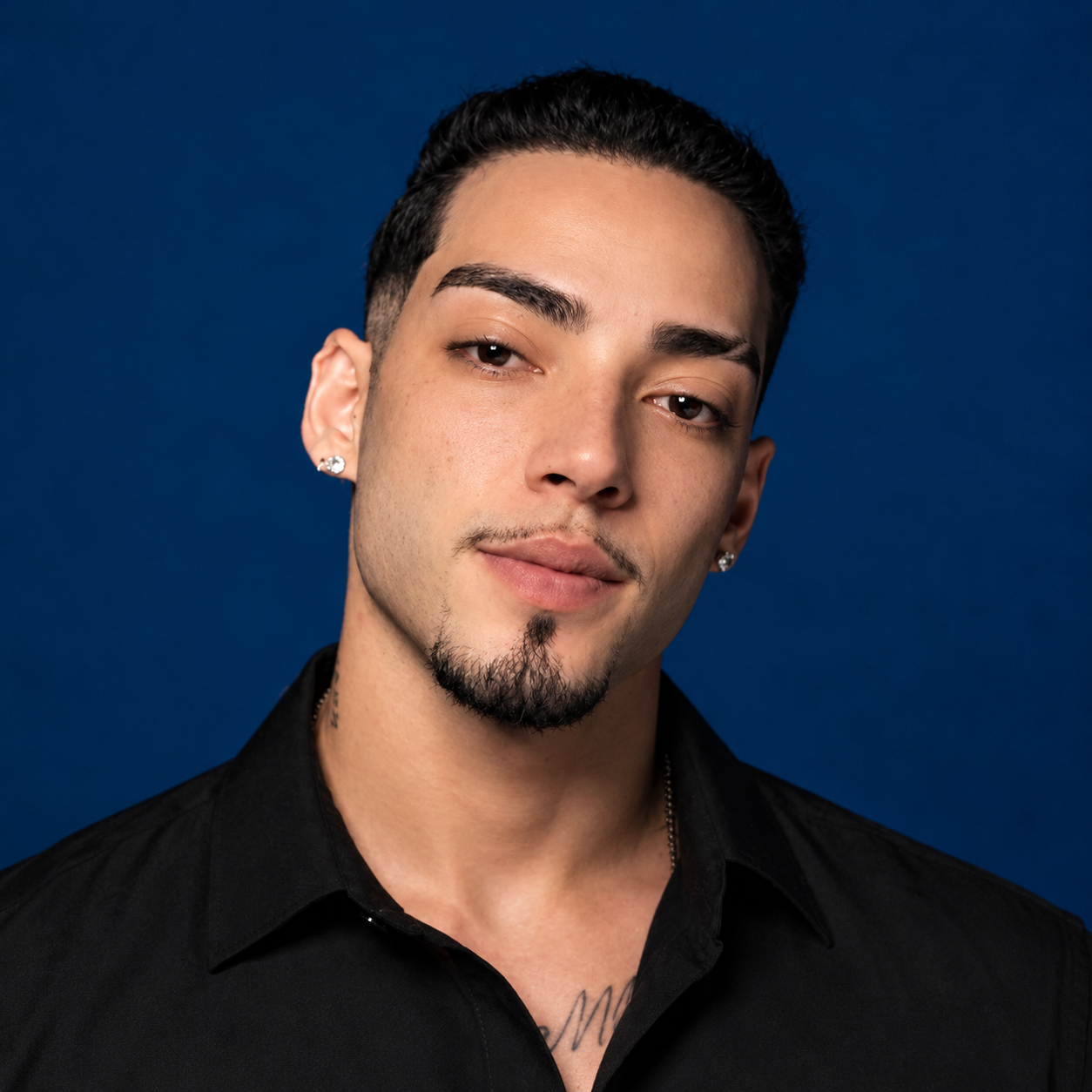 Vitor Coronato, de camisa preta, em retrato sobre fundo azul.